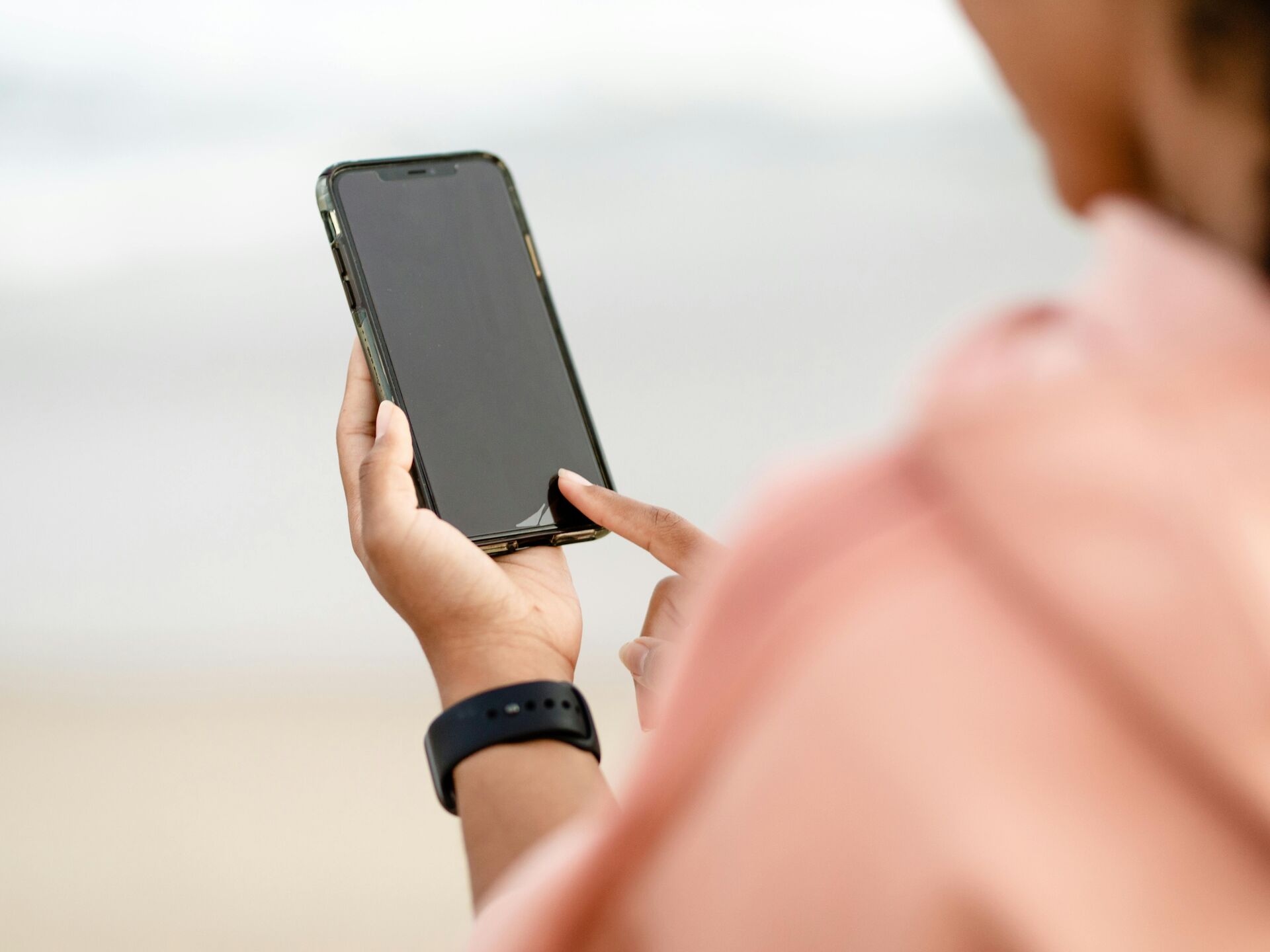 Nahaufnahme einer Person, die ein Smartphone in der Hand hält und den Bildschirm berührt.