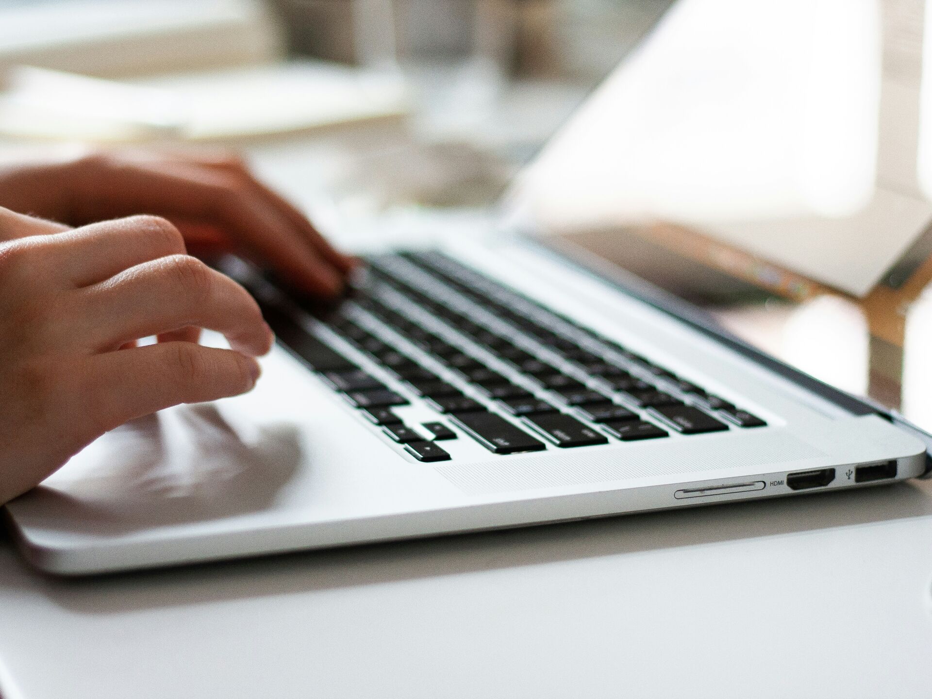 Nahaufnahme einer Person, die auf einer Laptop-Tastatur tippt, mit Fokus auf den Händen und den Tasten.