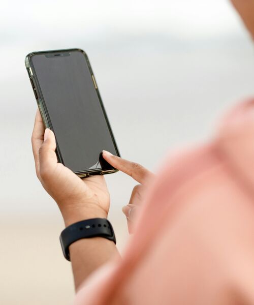 Nahaufnahme einer Person, die ein Smartphone in der Hand hält und den Bildschirm berührt.