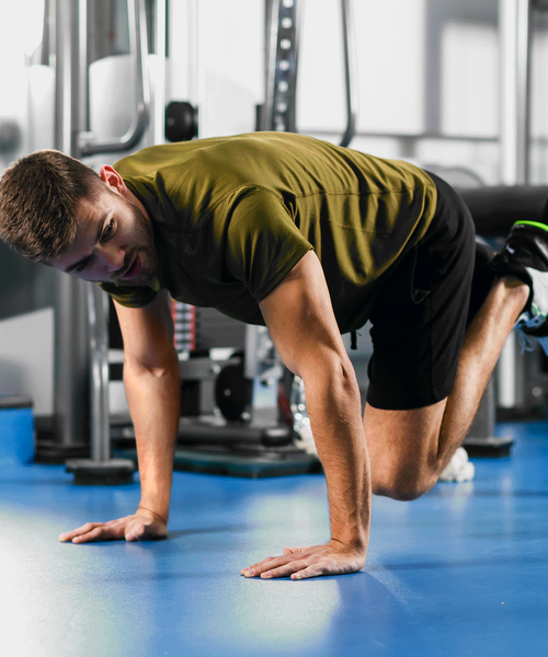 Person macht eine Fitnessübung auf dem Boden in einem Trainingsraum.